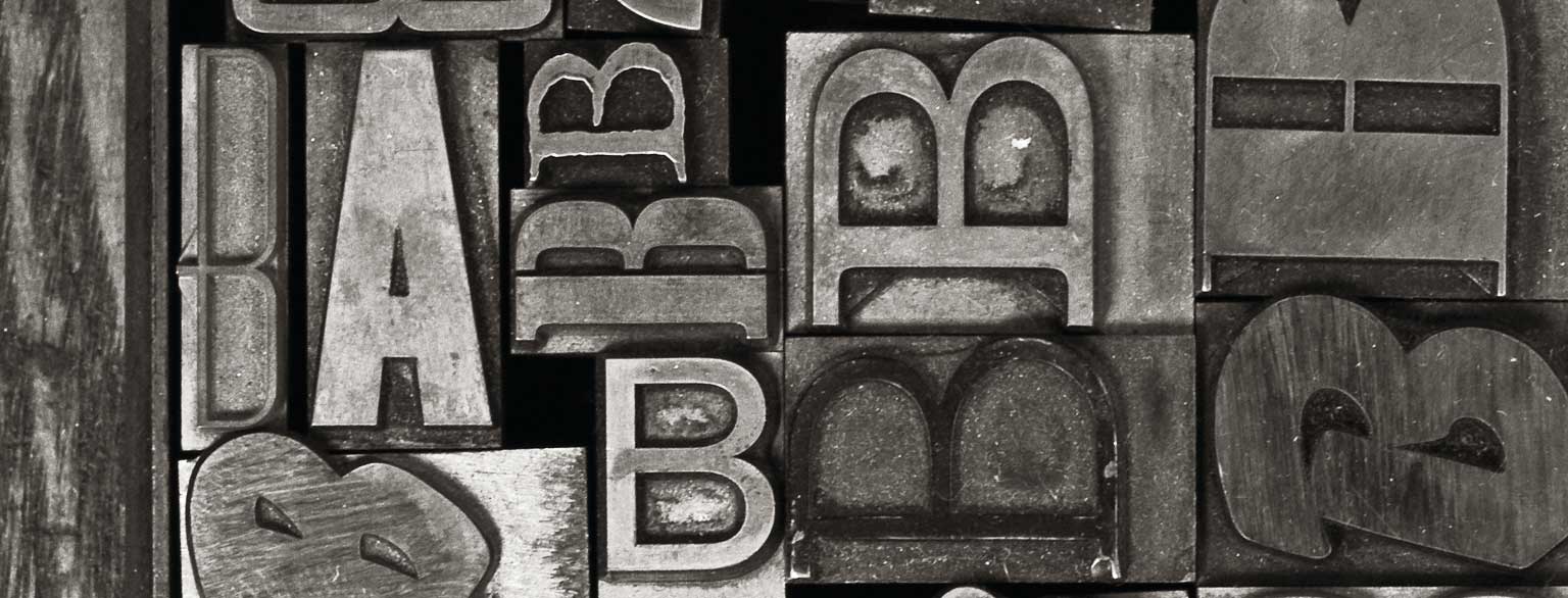 Masthead Graphic: A variety of ‘A’ and ‘B’ metal type sorts for handset letterpress printing in a resorting tray.